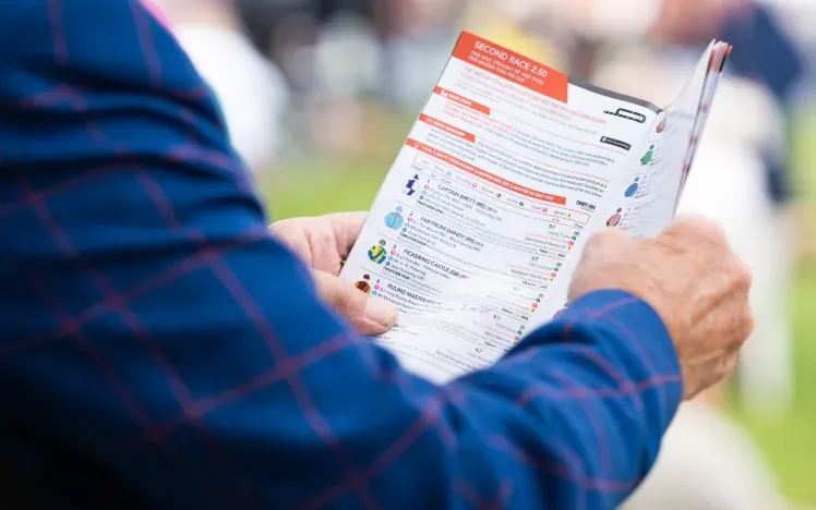 A racegoer in a suit studies the racecard at Great Yarmouth