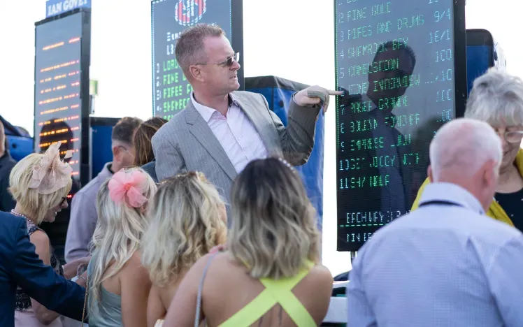A bookmaker talking through the odds with a group of race goers
